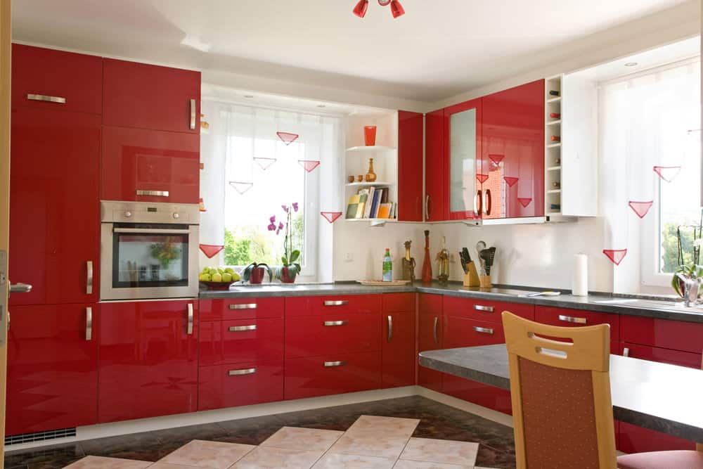 l型厨房，现代化的红色橱柜，灰色的台面和白色的墙壁。我认为地板也应该是白色的。