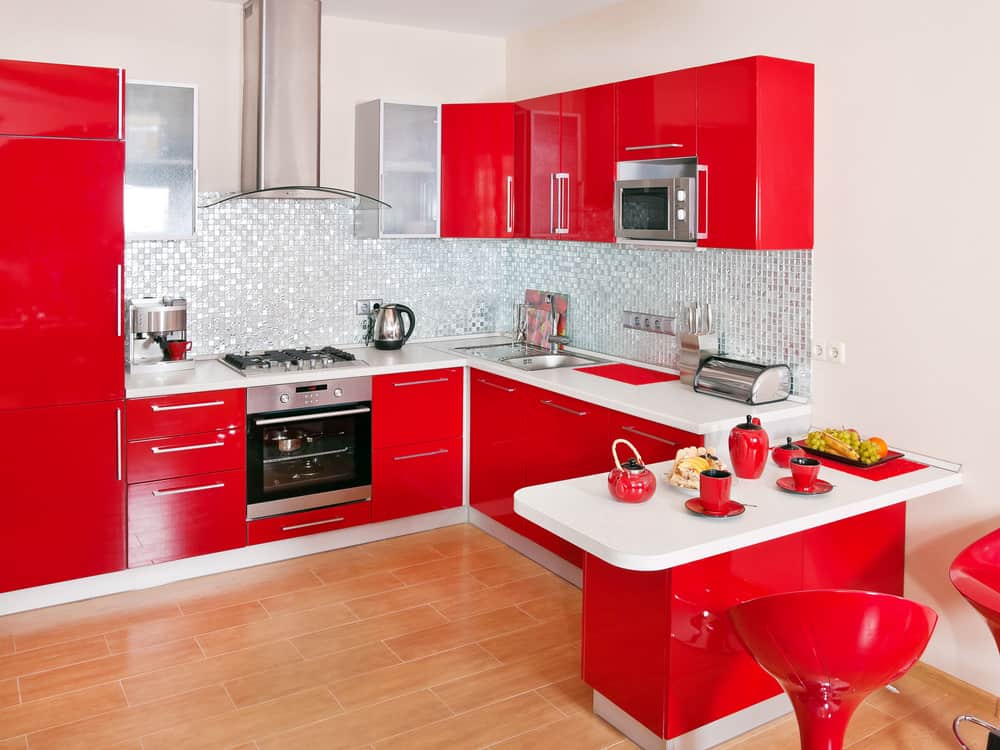 小公寓红色厨房，当代设计，白色台面和浅蓝色后挡板。