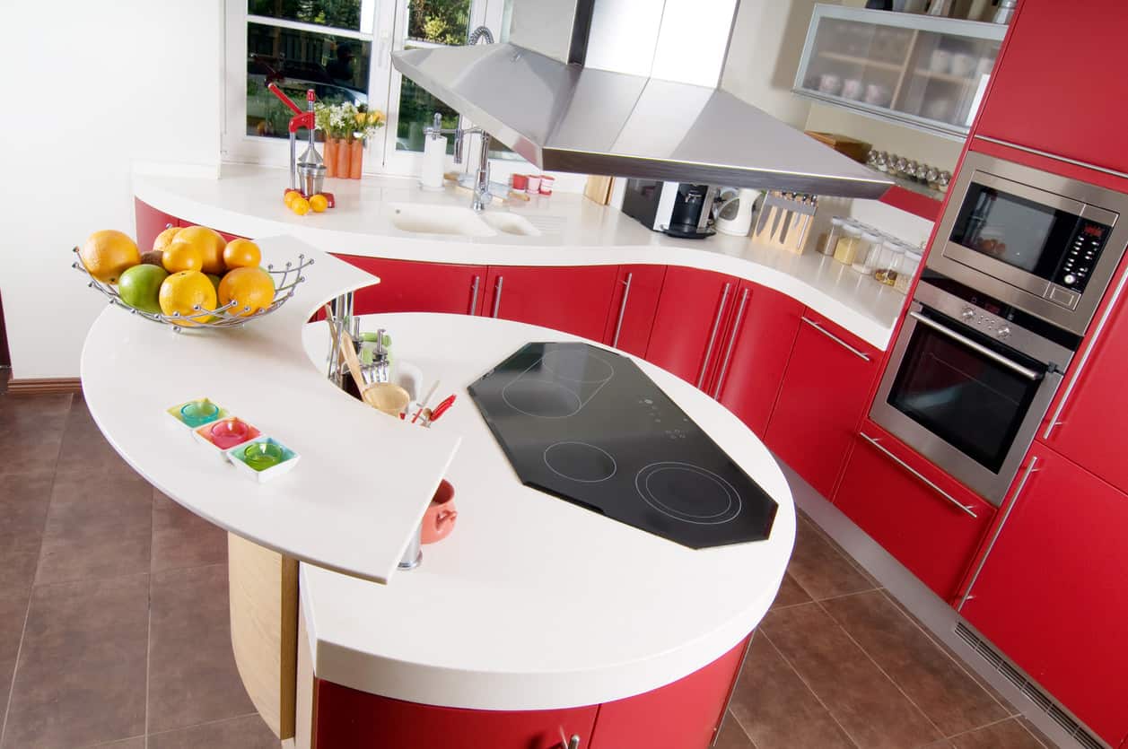 红色厨房搭配明亮的白色台面，曲线运用得很好。小圆岛与整个厨房的橱柜相匹配。这是一个有趣而异想天开的厨房设计。