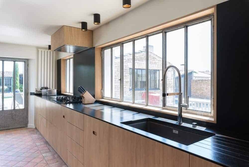 现代厨房，黑色台面和黑色后挡板，以及玻璃窗。