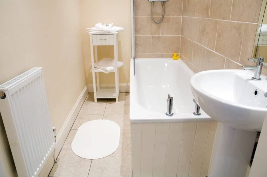 小浴室，有一个小浴缸-淋浴组合，底座水槽，茶几和加热器。