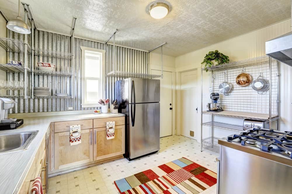 明亮的厨房配有不锈钢板条货架，不锈钢家具和带区域地毯的瓷砖地板。