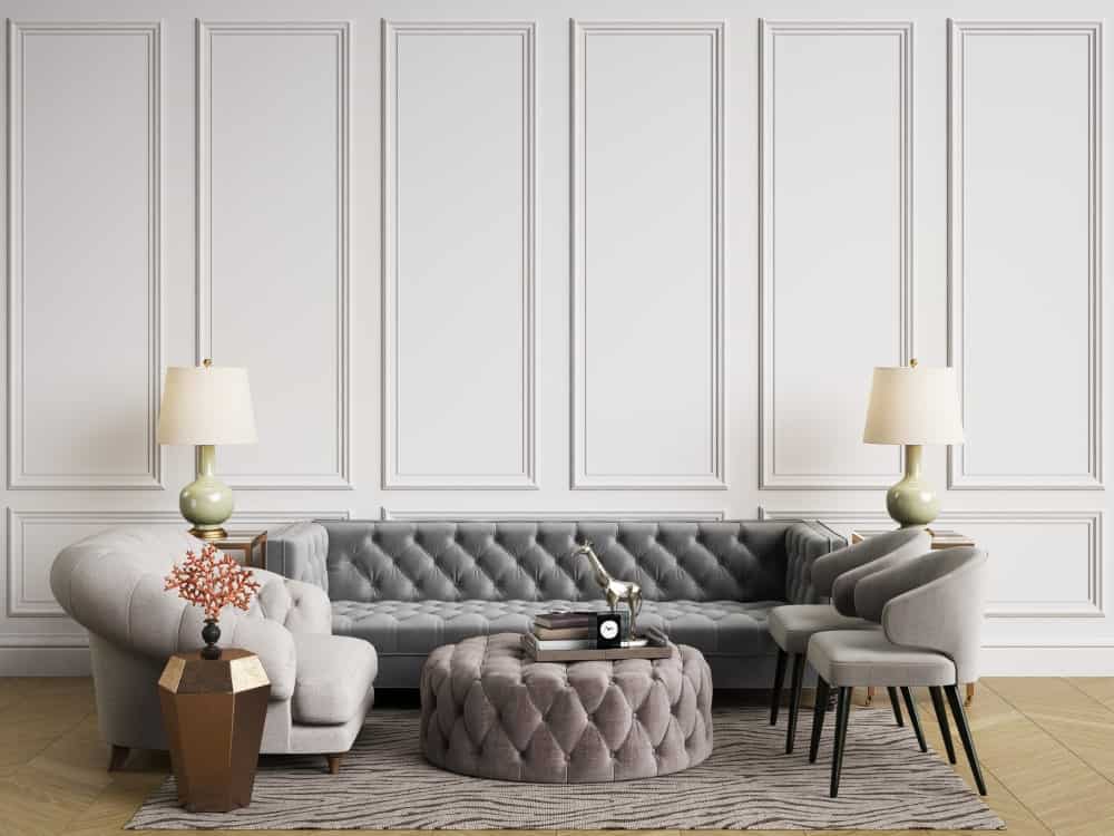 优雅的客厅，有盒式护墙板，一对灯罩之间有一个簇绒沙发，两侧有一个时髦的扶手椅。