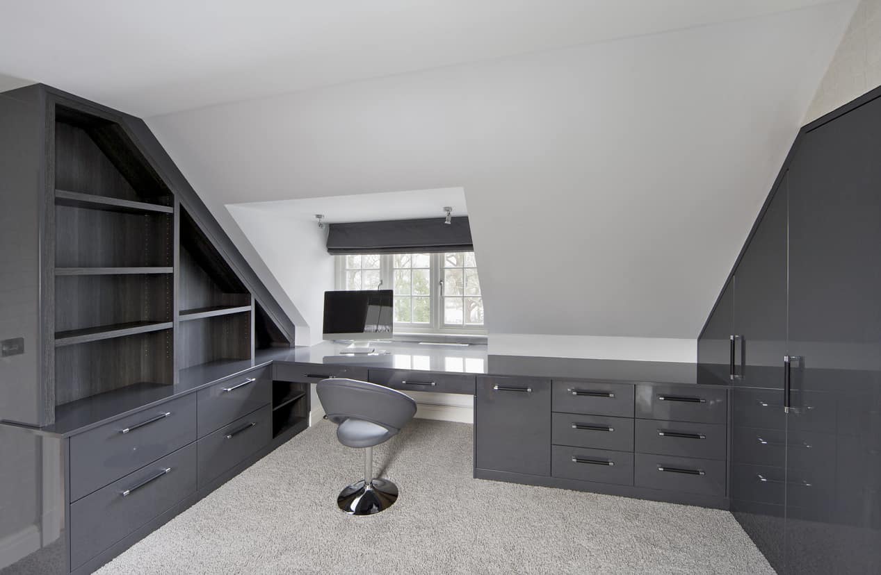 一个时尚的家庭办公室，有时尚的灰色橱柜和内置的桌子和椅子，放在地毯地板上。