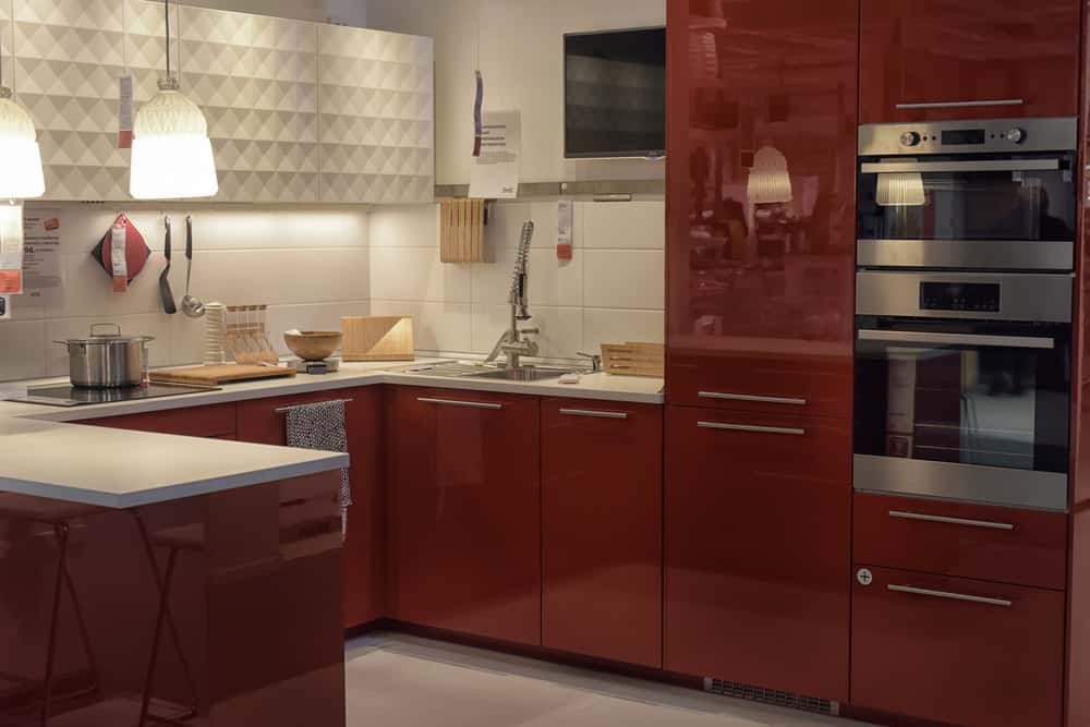 这个厨房里的固定装置模仿红木美丽的深红色。墙壁和地板采用柔和的白色和灰色色调，吊灯提供了充足的光线，照亮了房间。