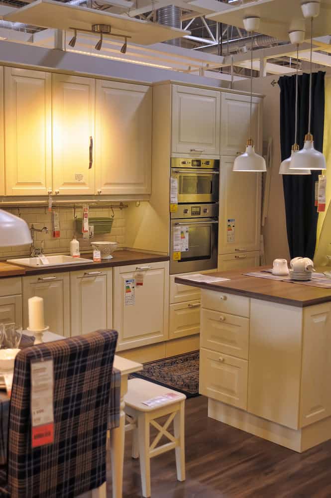 这个小而舒适的厨房有一个非常欢迎的气氛。家具和固定装置是柔和的奶油色。厨房桌子旁的棕色格子扶手椅和温暖的金色灯光进一步增加了厨房的家常感。