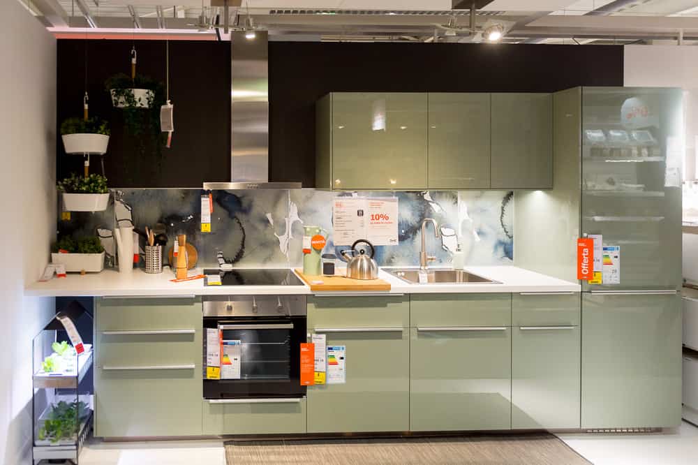 这个可爱的厨房用柔和的色调和深黑色的后墙完成。橱柜是漂亮的淡薄荷色，但薄荷色的后挡板有着美丽的旋转蓝色和白色，与厨房里的直线形成了平衡。这是一个漂亮的极简风格的厨房。