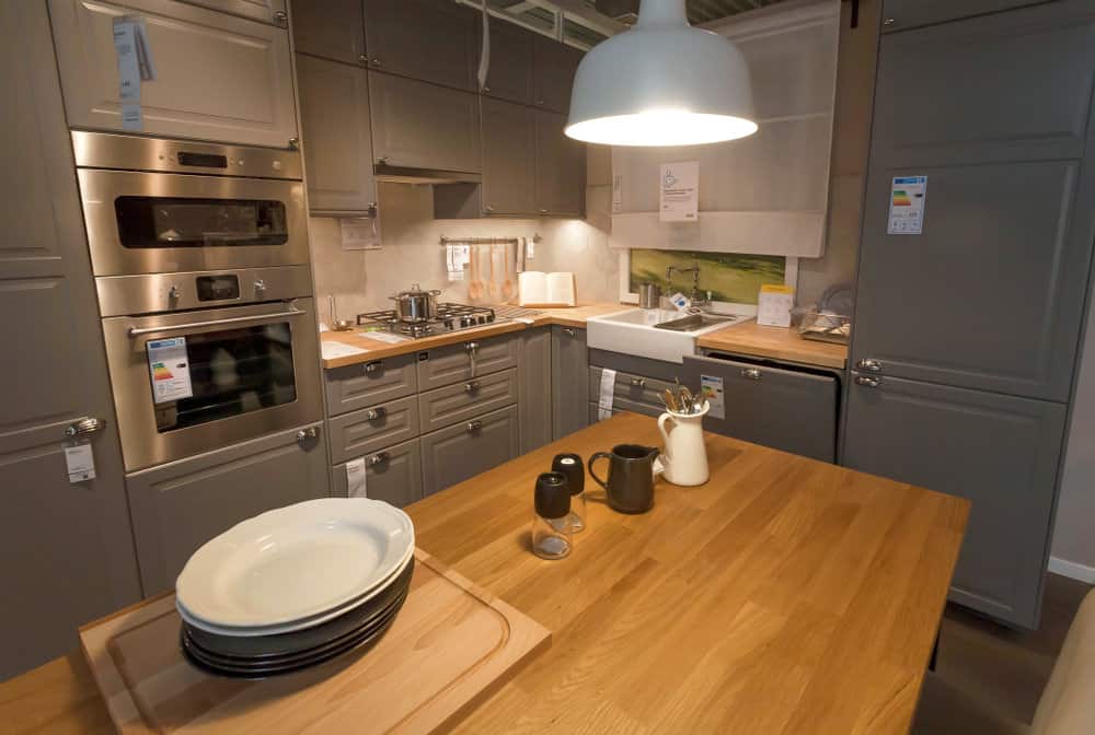 厨房由银色电器、钢固定装置和混凝土颜色的家具组成。厨房中间的金色木岛台占据了大部分空间，与厨房的冷色调形成了温暖、美丽的对比。