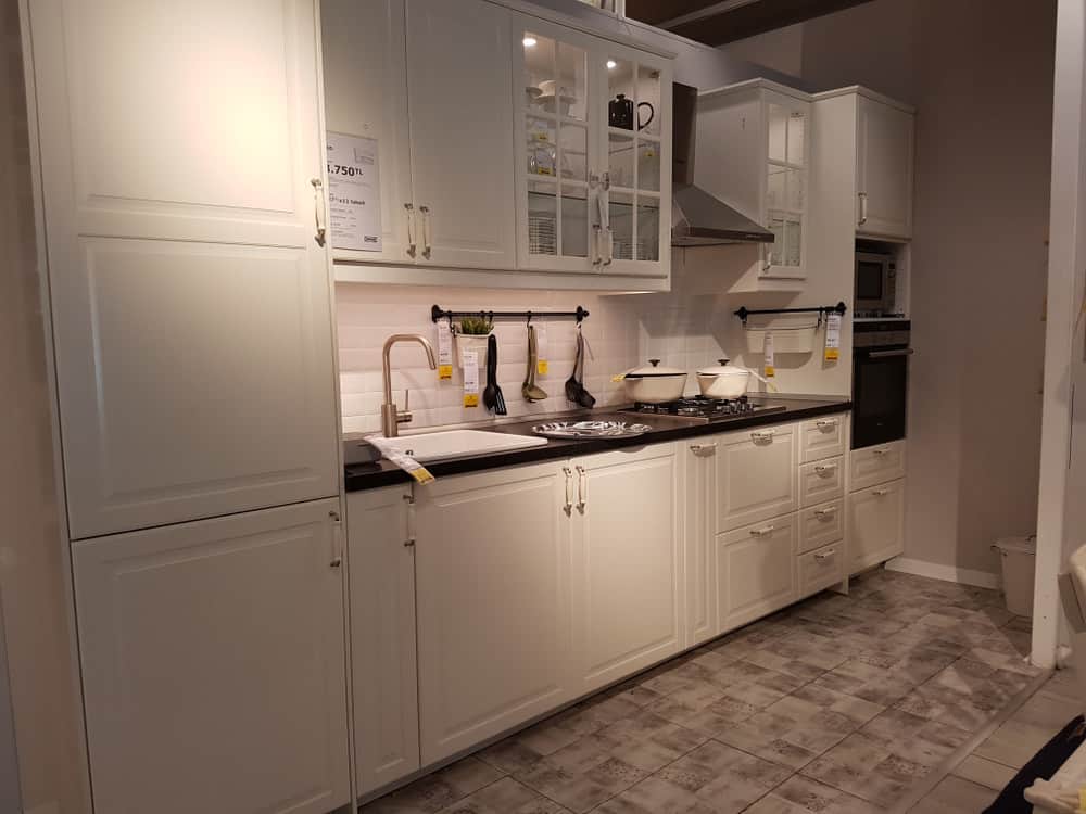 虽然这间厨房相当狭长，但它看起来并不是那样，因为它的高墙和乳白色的橱柜。地板以温暖的泥土色调呈现，为这个烹饪区带来了可爱的温暖。