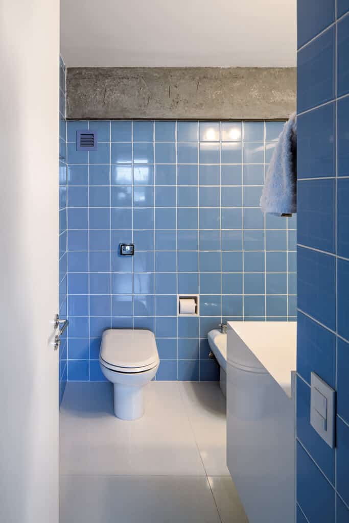 这间浴室的墙壁是蓝色瓷砖，地板很简单，简洁明了。这个房间没有杂乱，线条干净，但可爱的蓝色墙壁平衡了这个原本荒凉的房间。