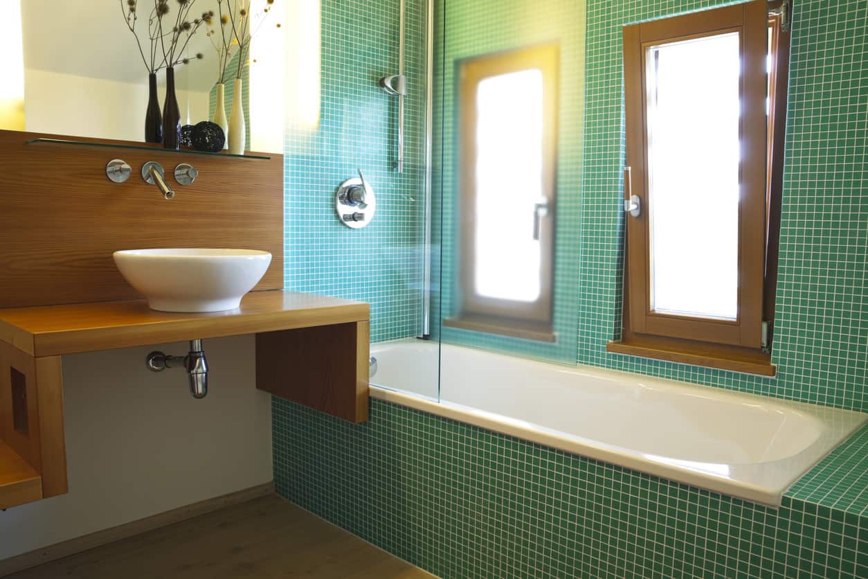 浴室有一半的灵感来自日本文化，从简单的木制水槽架和瓷碗到细长的黑色花瓶里的小花枝。另一半由环绕浴缸的深绿松石瓷砖并置。