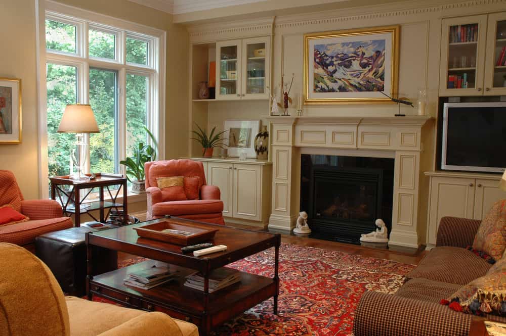 粉红色的扶手椅和红色的波斯地毯使这个格鲁吉亚殖民风格的家庭房间充满活力