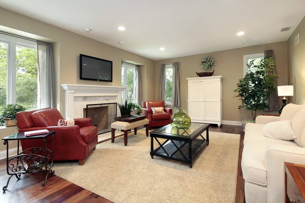 深红色的皮革扶手椅和丰富的棕色木地板是明亮的口音,这否则苍白的客厅