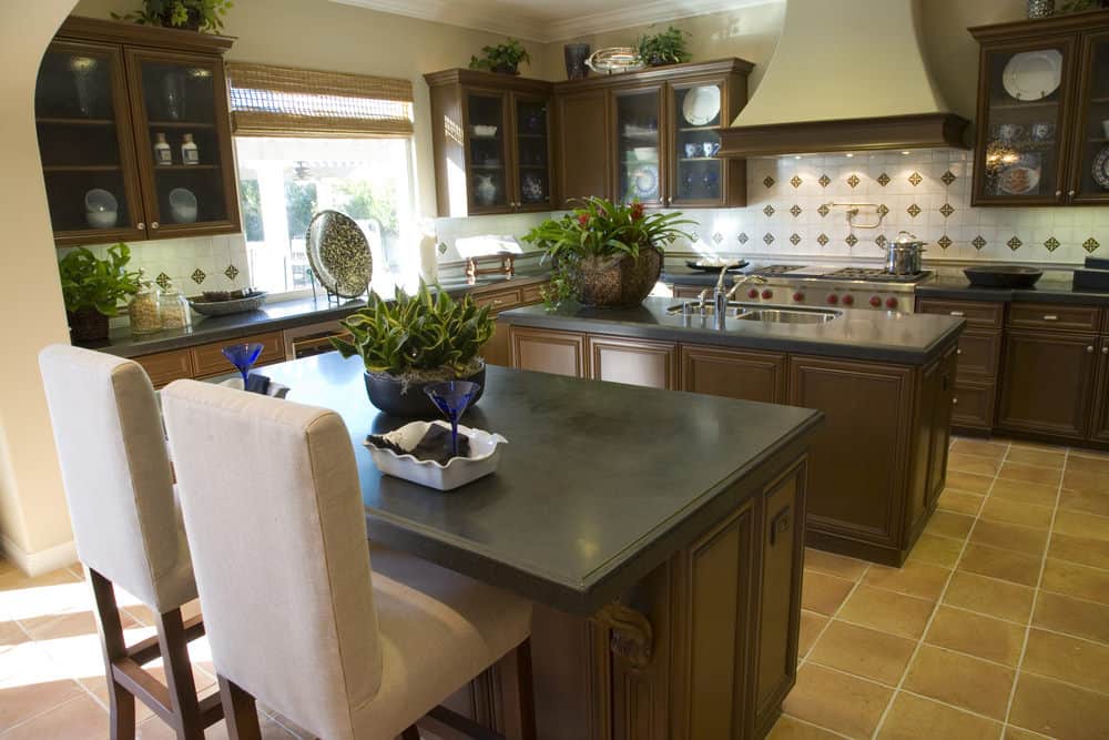 对于那些喜欢泥土色调的人来说，这个紧凑的厨房非常适合小家庭。侧面的柜台上摆放着舒适的椅子。自然采光和室内低亮度与地板完美搭配。