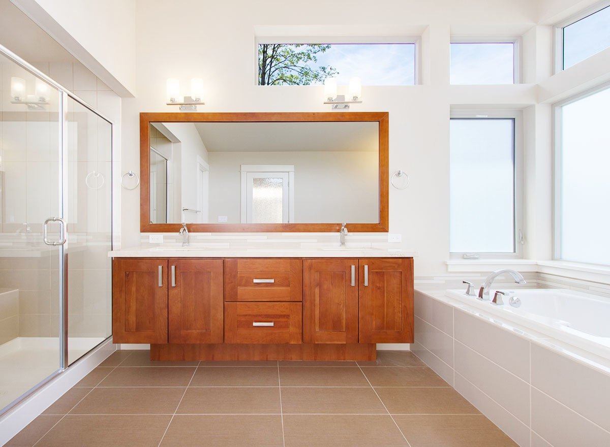 双水槽梳妆台的镜框镜子和木橱柜打破了这个主浴室单调的白色方案。