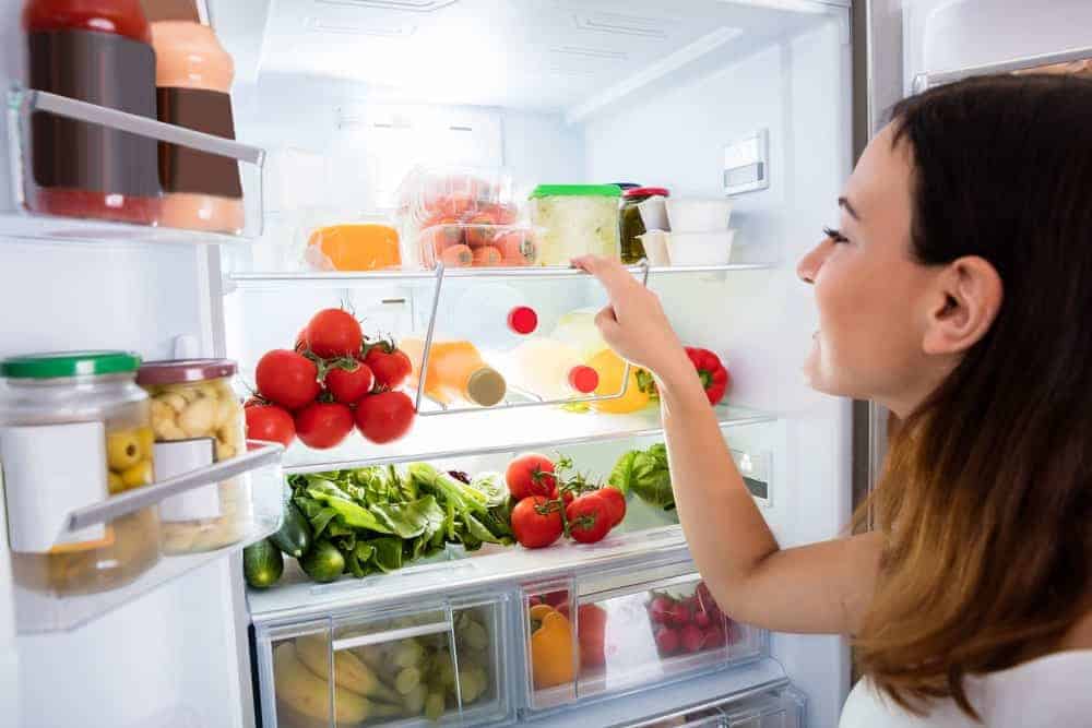 妇女检查冰箱里的食物。