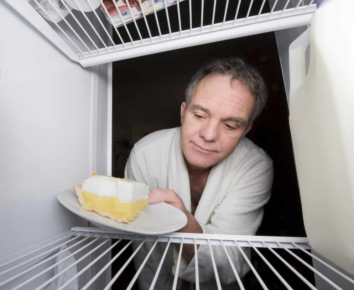 一个男人在冰箱里放了一片柠檬蛋白派。