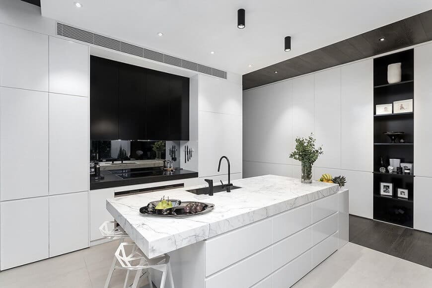 黑白颜色的组合是永远不会过时的。这个明亮的厨房也利用了它。它干净整洁，恰到好处地平衡了两种色调。黑色的水槽嵌在白色的厨房岛台上，黑色的面板架从上到下靠在白墙上，这是利用这些阴影的一种体面的方式。