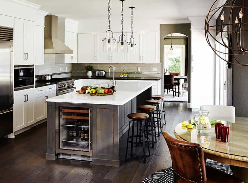 这个厨房精致的秘密在于它以不同色调和不同材料的独特组合为特色。橱柜和厨房岛台均为纯白色，与深色木地板形成鲜明对比。悬挂在天花板上的光滑的灯具和角落里一个真正别致的圆形金属球灯将迷人的设计带到了一个完全不同的水平