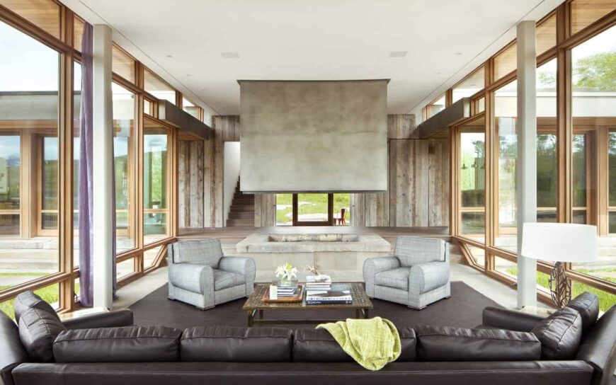 壮观的现代客厅有着质朴的风格，黑色沙发面对着黑色地毯上的两个灰色单人沙发。