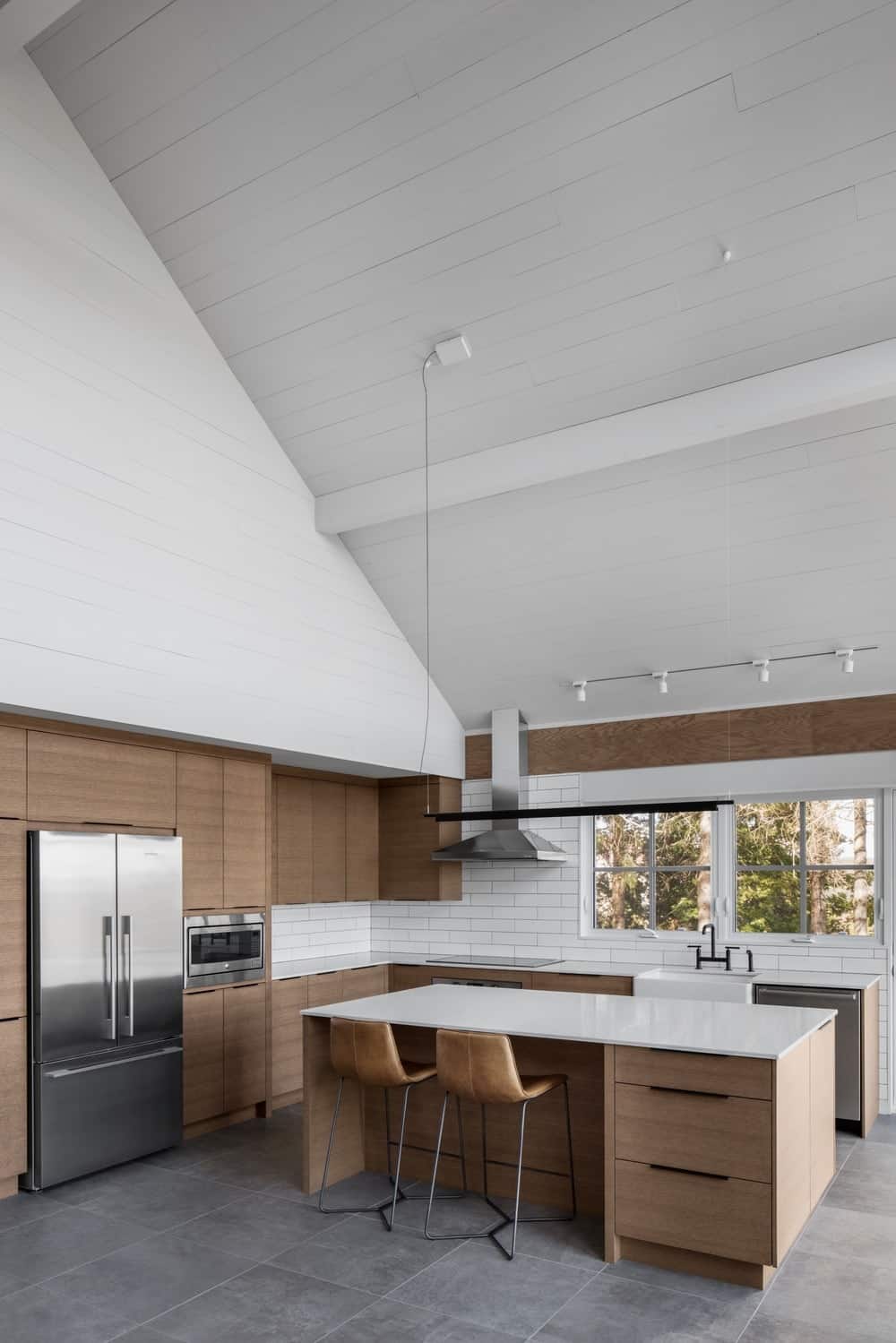 这种设计的简单性使我们感到困惑。其原始的白色台面与普通的有机木材搭配，是俯瞰高大绿色树木的厨房的终极选择。此外，将高端屋顶漆成完全白色，使这个地方看起来更加开放，并将人们的注意力集中在厨房上。