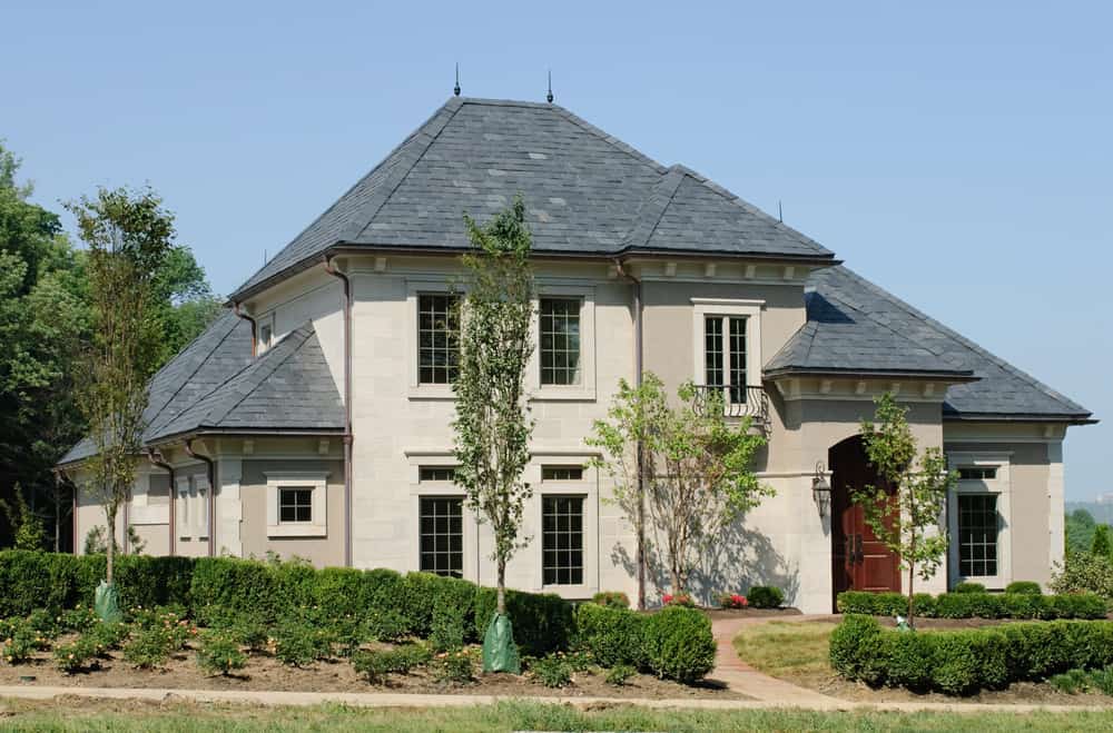这个奶油色和灰色的房子是我们所见过的最好看的屋顶房子之一。冷灰色的屋顶与淡奶油色的墙壁很好地平衡。中性色调被一扇深红色的门所抵消，为这座美丽的房子增添了一抹亮色。