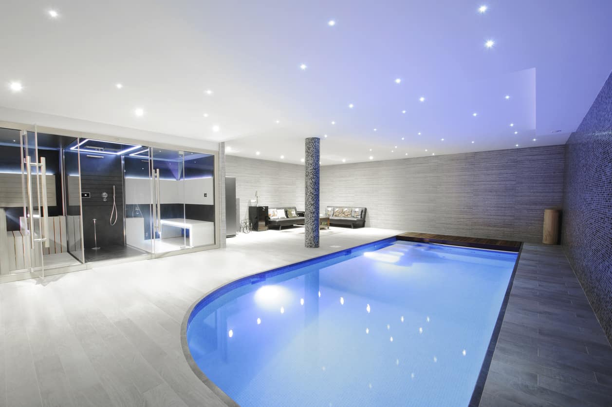 这个室内游泳池是一个相当辉煌的展示，有一个角度的设计，美丽的灰色内饰和天花板上柔软的闪闪发光的灯，看起来像夜晚的星星。