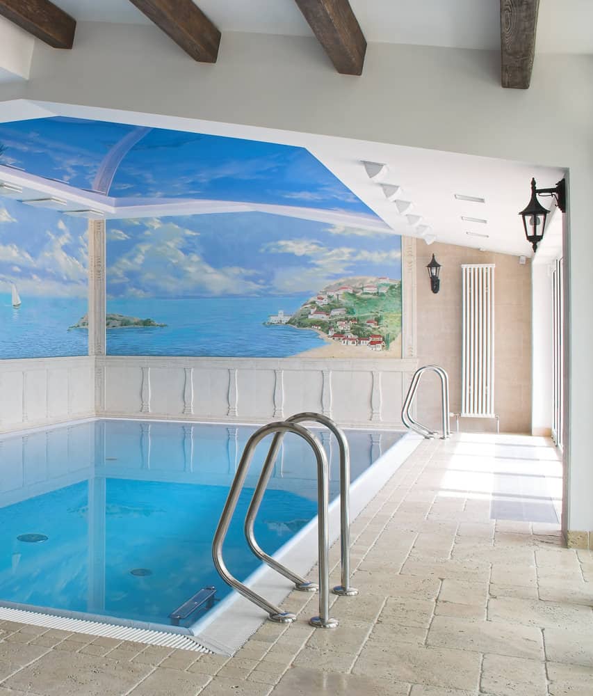 这个室内游泳池看起来就像农舍里常见的游泳池。这是一个简单的游泳池，白色的外观，一个巨大的窗户一直到天花板，提供了一个华丽的户外景观。