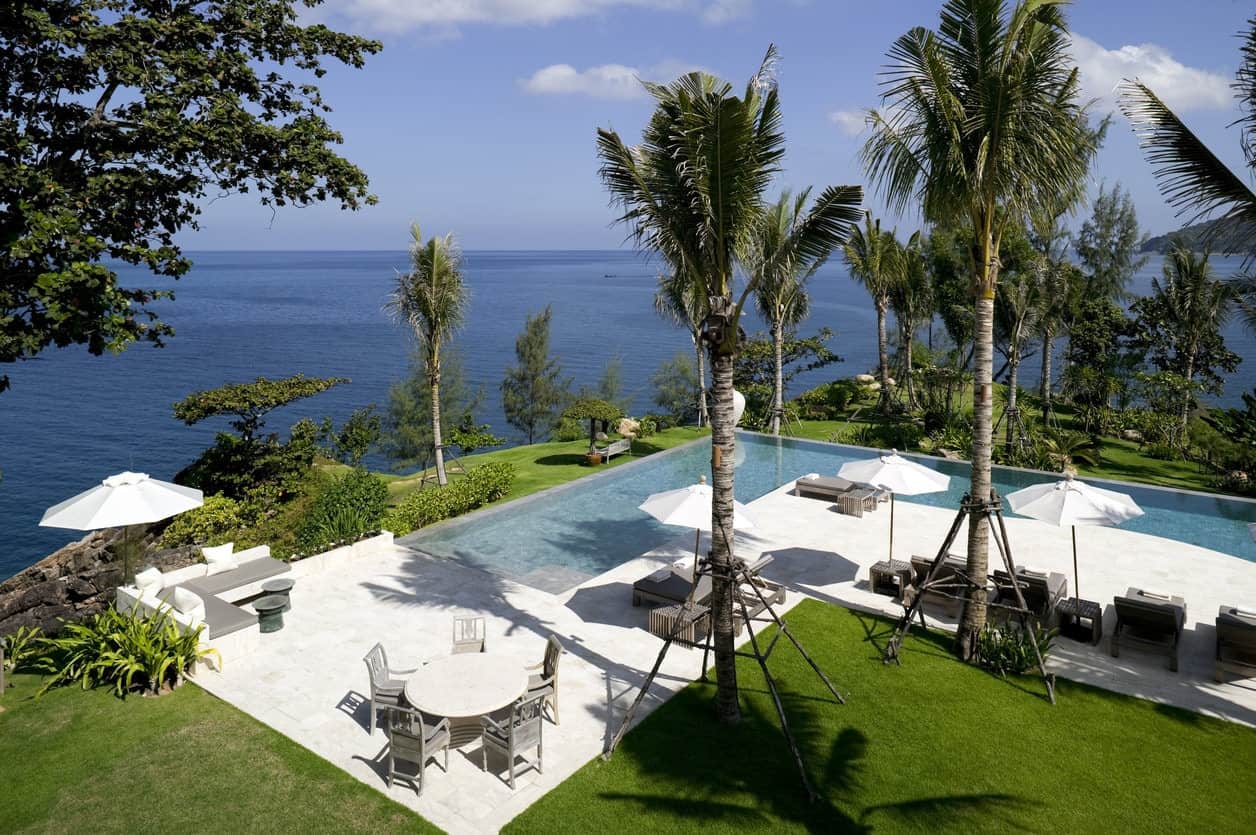 豪华l型游泳池，配有棕榈树和露台家具。