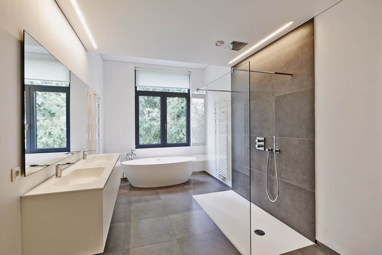 一面巨大的镜子，中性色调的瓷砖和简单的固定装置使这个浴室吸引人，同时是经典和现代的。