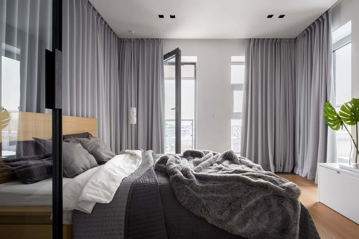 简单的当代主卧室，从地板到天花板的灰色窗帘提供广泛的隐私。