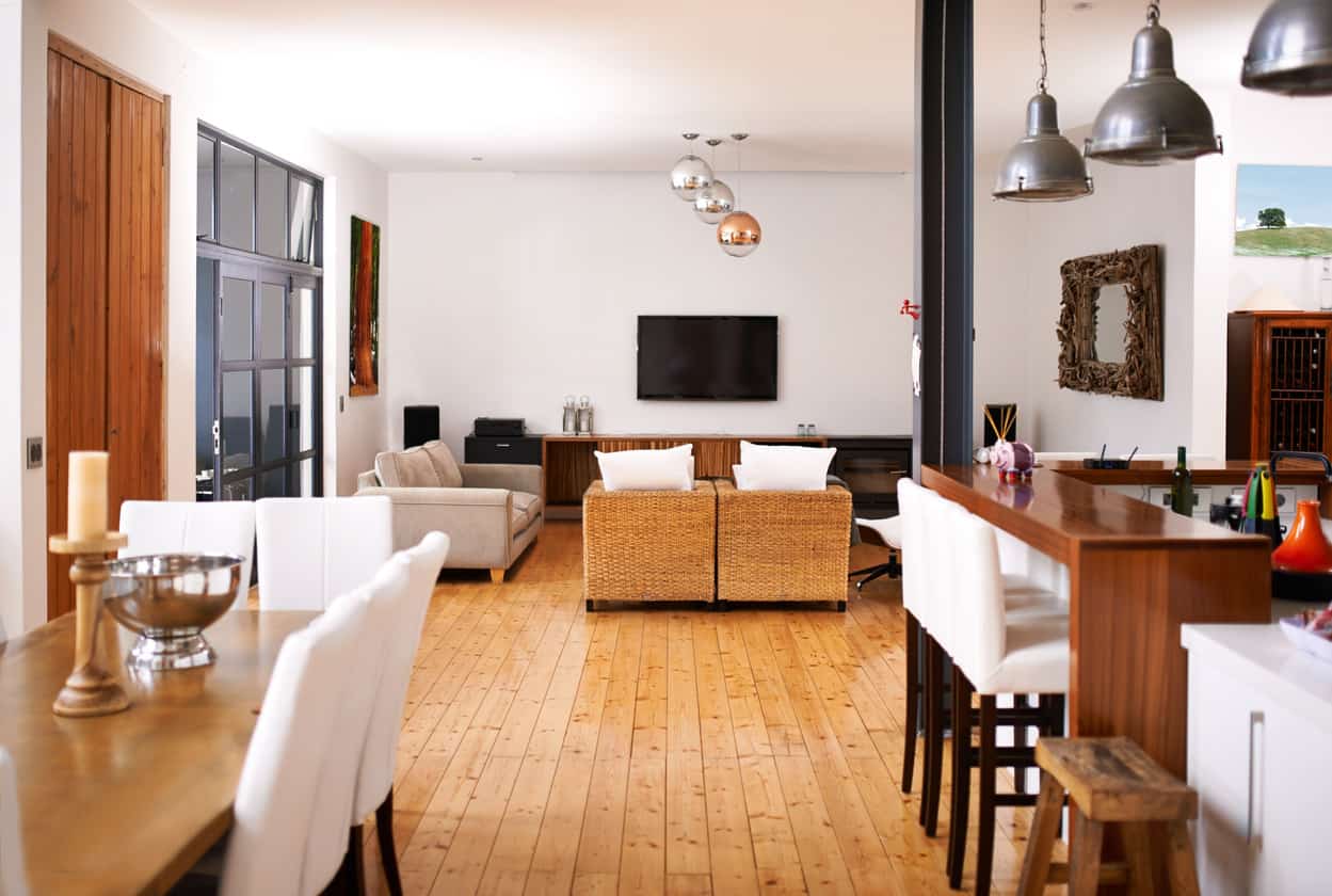 这种实用的设计以厨房和用餐区为特色，可以俯瞰间距均匀的客厅。奶茶木地板给这个地方一个整洁的外观，而纯白色的毛绒座椅进一步增加了这一点。除了金属灯和LCD屏幕，这个棕色木制主题的开放房间让人想起一个体面的小屋。