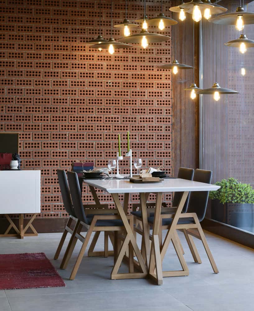 这种餐厅风格的伟大之处在于许多顶灯散发出温暖的金色光芒。家具遵循现代设计美学，易于清洁和维护。但用餐区最引人注目的特点是红砖墙，上面布满了数百个小格子。