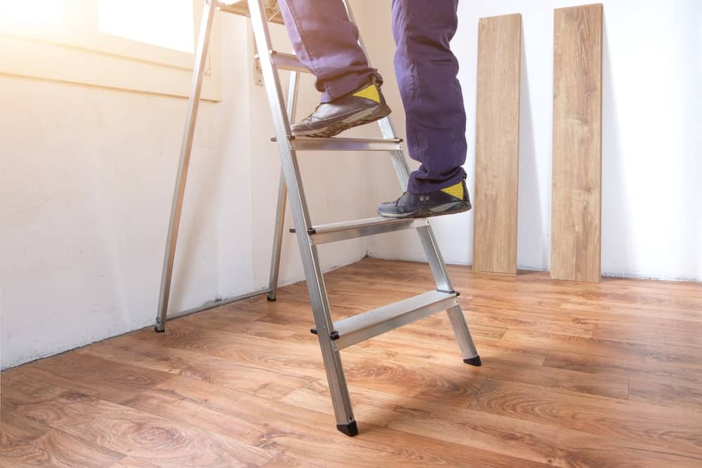 播种的射击一个人的脚爬上或向下一个梯子在有木地板的房间里面。