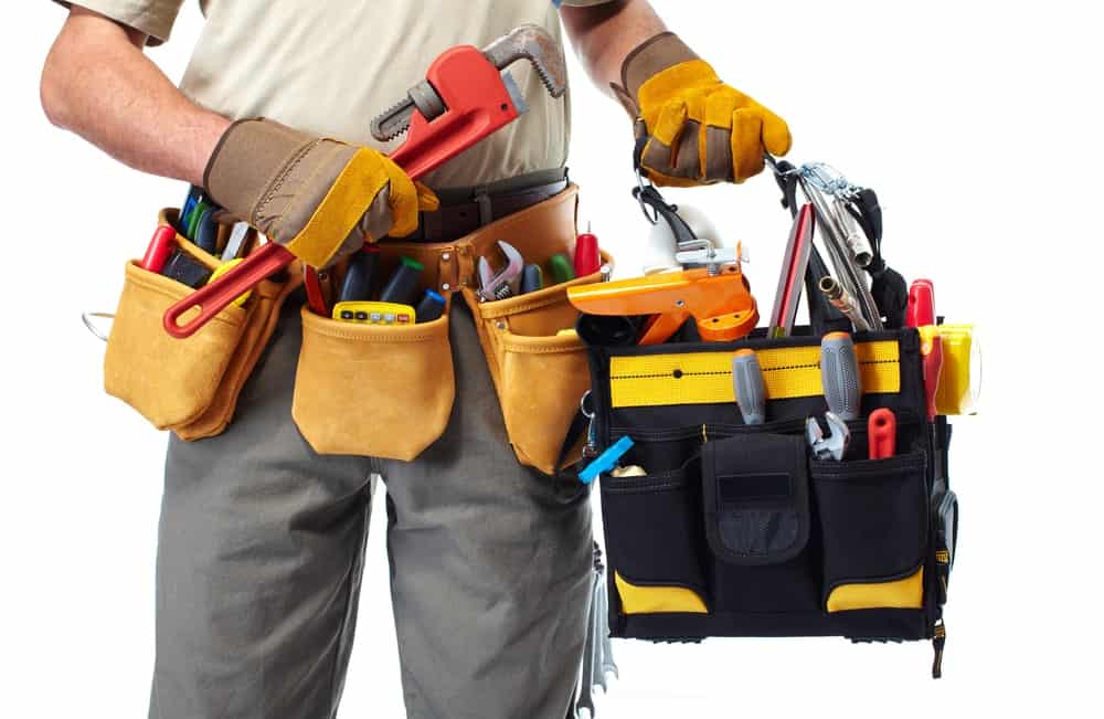 戴工具传送带和拿着一个装满工具的袋子的工作者。