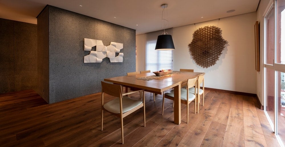 这是公寓的餐厅与相匹配的一个木制的餐桌硬木地板和固定在墙上的雕刻的一个部落面具在对面的墙上。