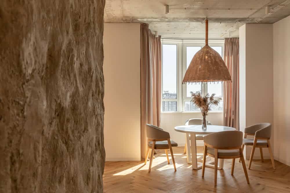 这是公寓的一个视图的用餐区变形石墙。白色的顶部设有一个柳条编织圆餐桌罩吊灯。这是由MAKHNO工作室设计。