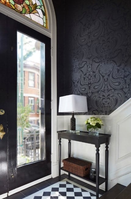 这个小而优雅的门厅设有时尚的瓷砖地板，白色和时尚的黑色墙壁和深色硬木楼梯的组合。