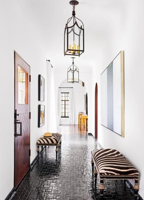 这个门厅拥有白色的墙壁和深色的瓷砖地板。座椅和墙壁装饰绝对完美结合，而小枝形吊灯为空间增添了亮度。