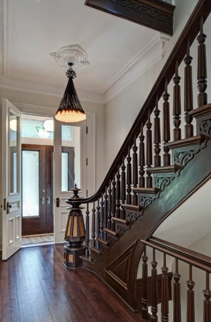 门厅以白色墙壁、棕色地板和楼梯为特色。枝形吊灯非常适合门厅的风格。