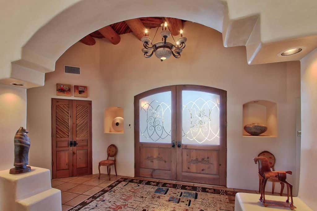 这个优雅的白色门厅带有棕色木制细节，与吊灯照明完美搭配。