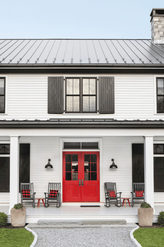 农舍的门廊上有灰色的摇椅和亮红色的门，由chango & co设计。