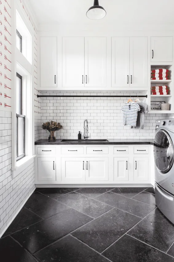 大的白色的洗衣房和定制橱柜水槽。白色的地铁瓷砖连壁。由chango & co。