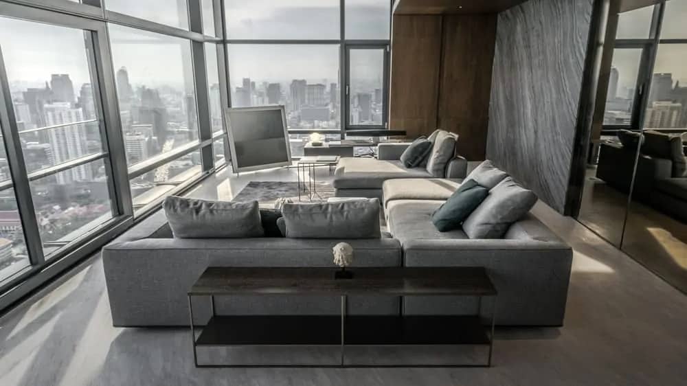 这一看是明亮和通风的客厅的公寓一套灰色组合沙发高大明亮的玻璃幕墙也展示城市的天际线的观点如下。由ONG&ONG设计的。
