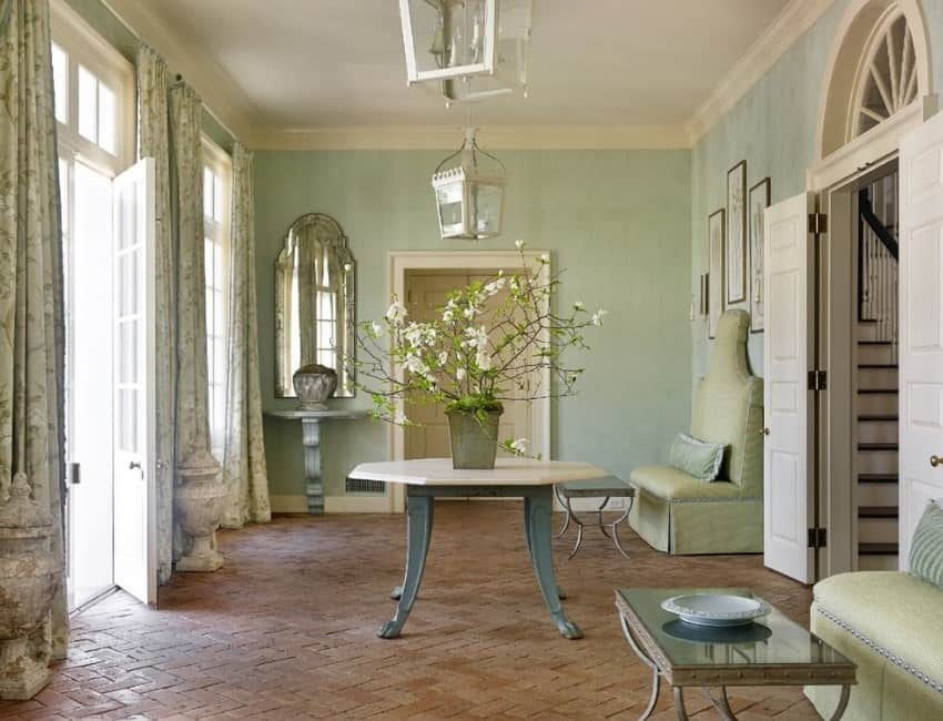 这个门厅以优雅的绿色墙壁和美丽的窗帘为特色，中心桌子上还有一株漂亮的室内植物。