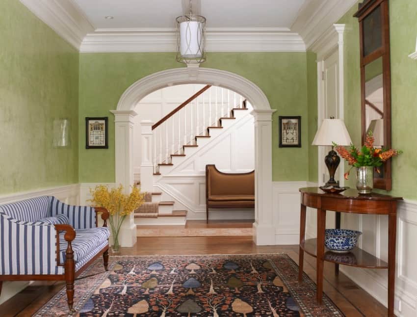 这个门厅的特色是一块非常迷人的地毯，与绿色的墙壁和白色的阴影相搭配。