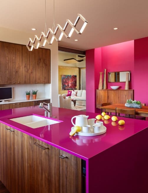 厨房岛和粉红色的工作台和木制的橱柜与粉红色的墙壁,面对木餐桌。