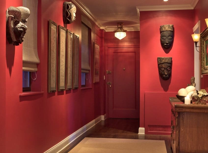 这个门厅以哑光红色墙壁为特色，有许多精美的墙壁装饰，由吊坠和墙壁照明照明。