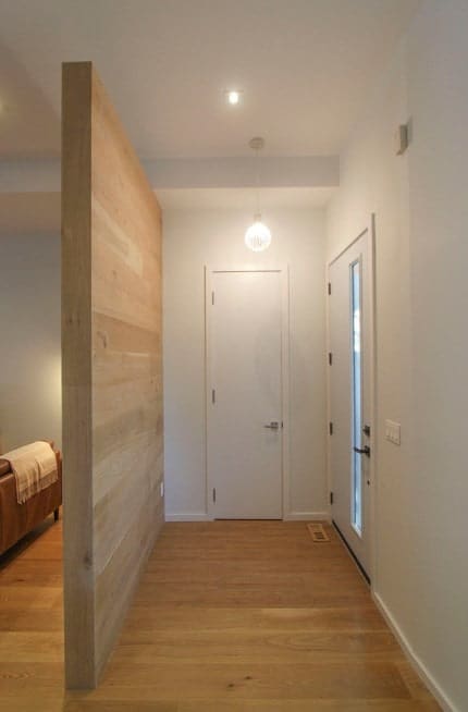 这个小门厅以乙烯基地板和白色墙壁为特色，由一个小吊灯照亮。