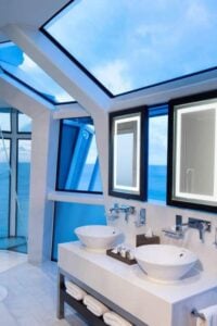 主浴室设有两个船水槽，周围有墙壁和天窗，可以看到广阔的海景和天空。